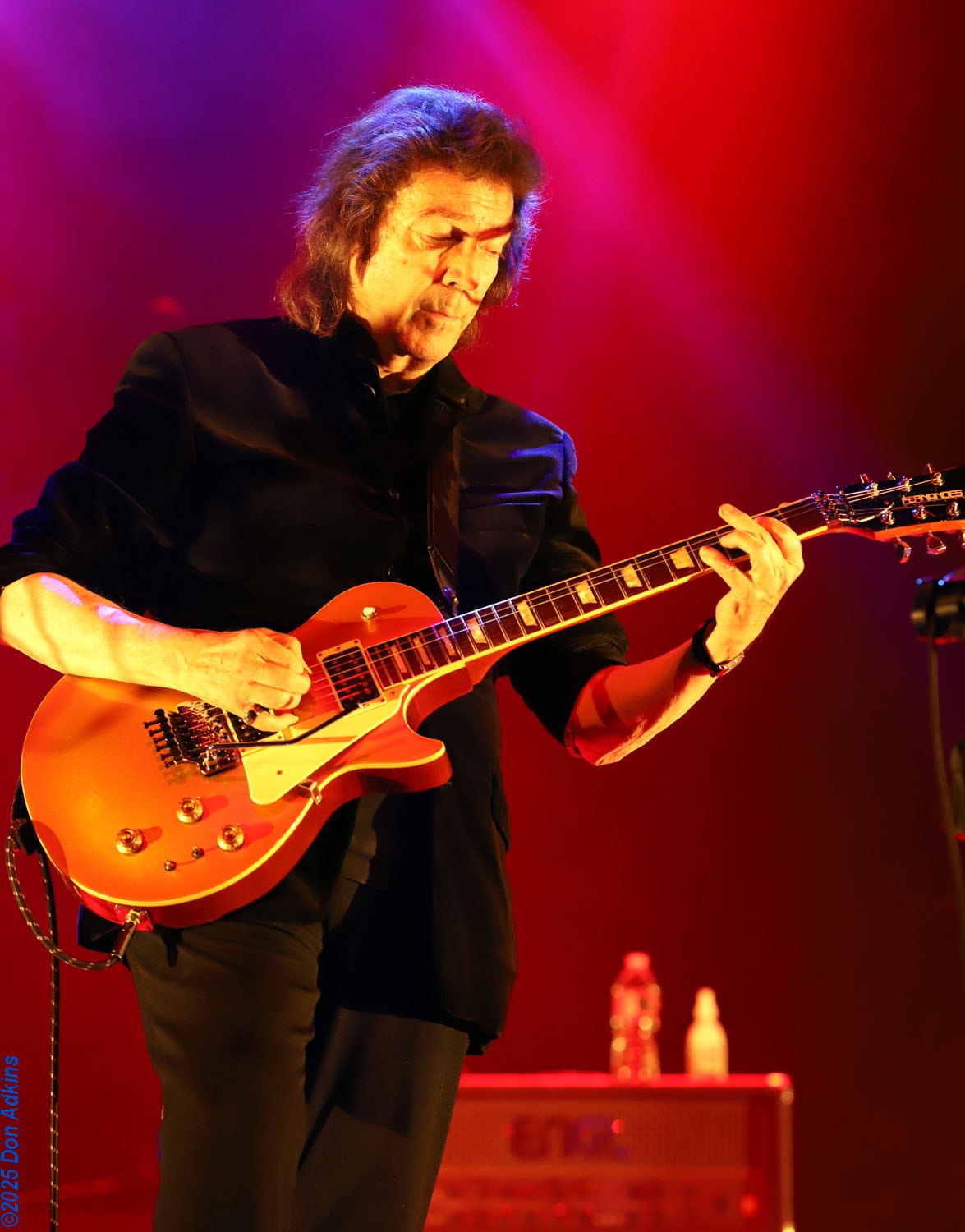Steve Hackett playing red Les Paul under pink and red stage lights