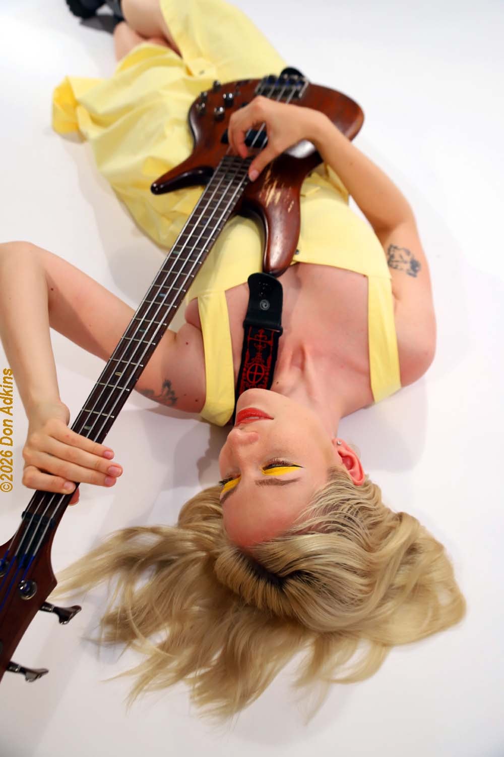 Lina Cooper playing bass guitar with yellow and pink tones